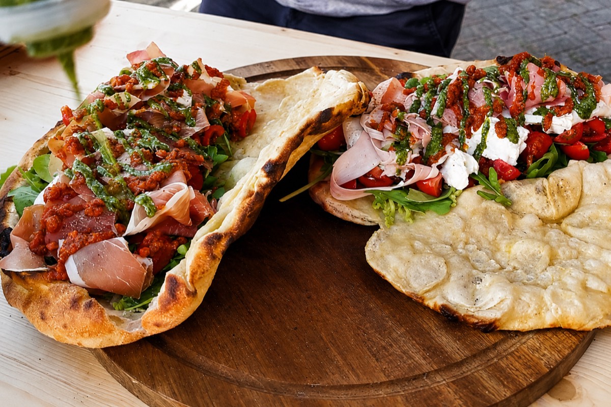 Neapoletanische Teigtaschen: im Steinofen gebackenes Fladenbrot, belegt mit Rucola, Prosciutto, Tomaten und Burrata
